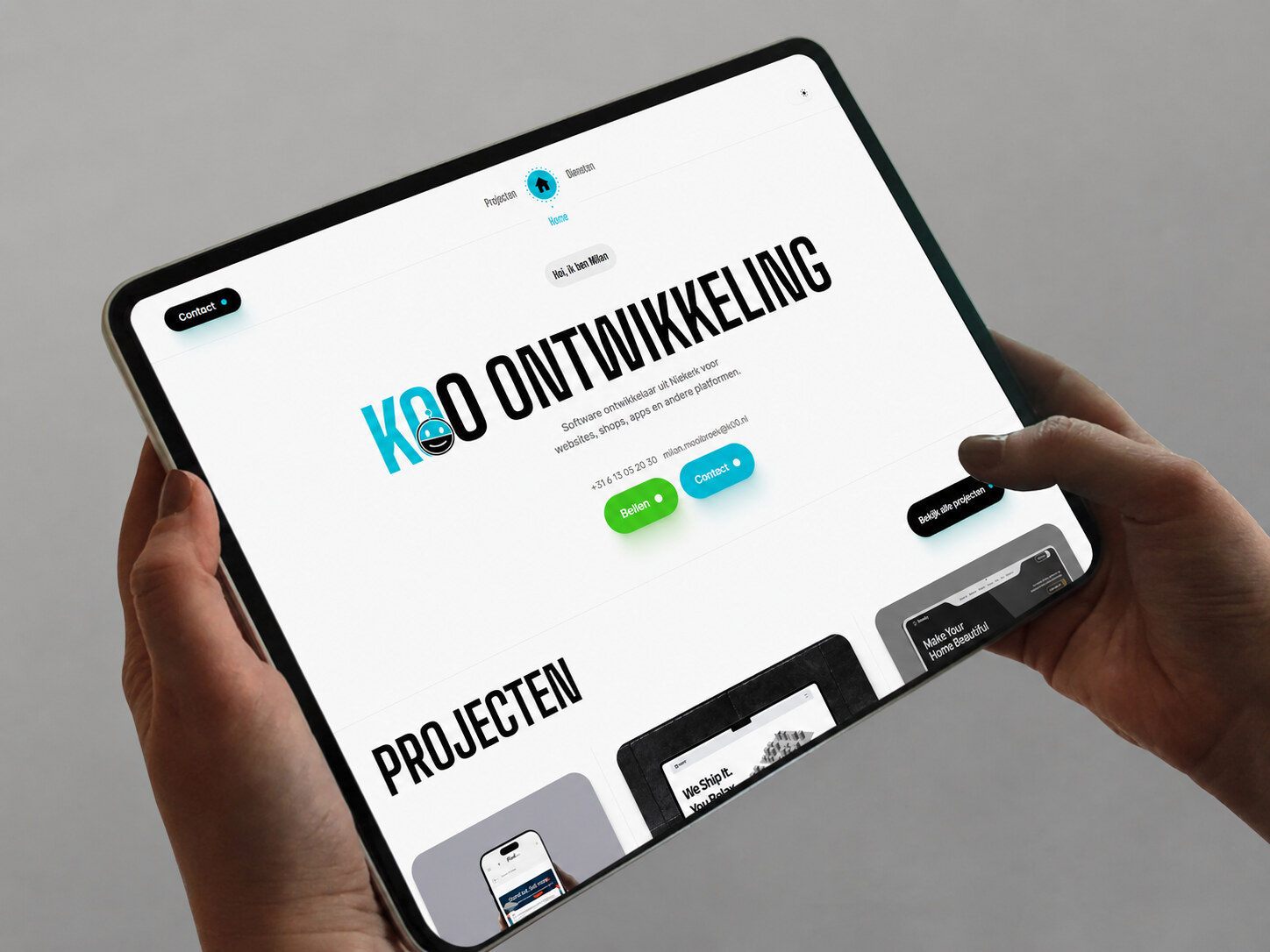 De K00 site live op een tablet, vastgehouden in twee handen